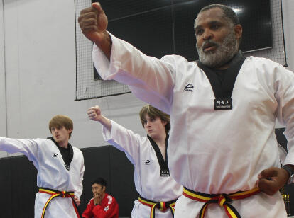 An adult student is performing a takedown technique on another student in class
