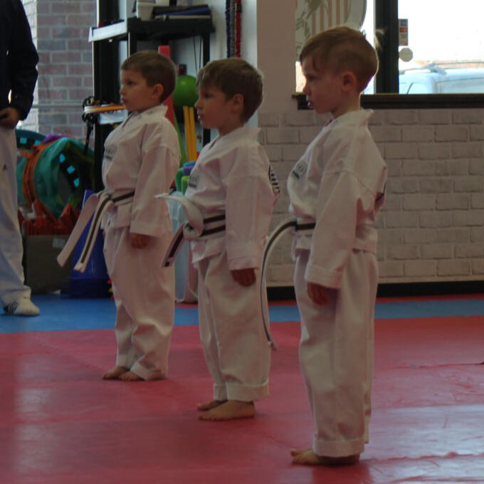Three 3-4 year old students standing in attention, awaiting instruction